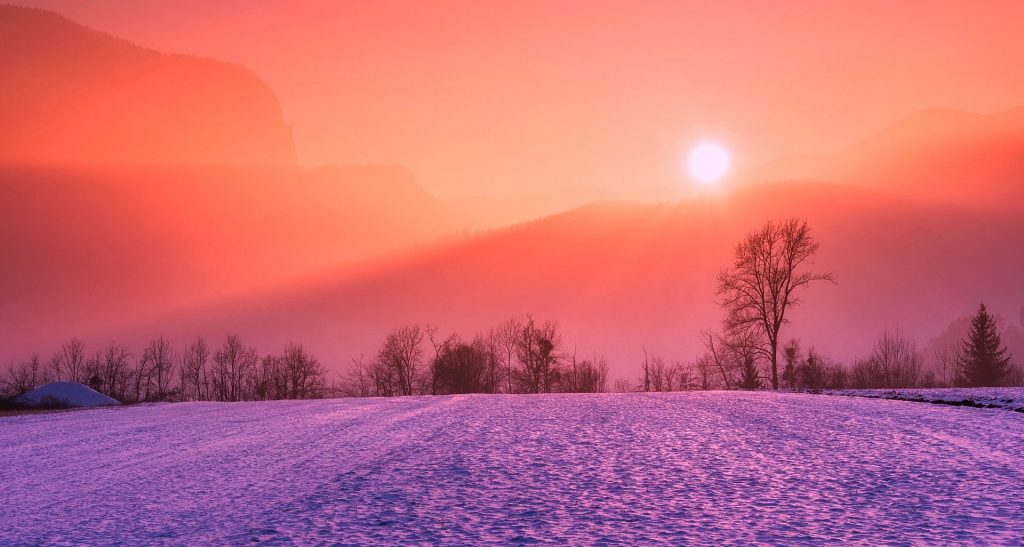 Imagem do inverno. Rua coberta de gelo. Ao fundo uma montanha com o nascer do Sol.
