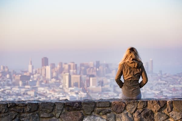 Mulher de costas olhando cidade ao fundo