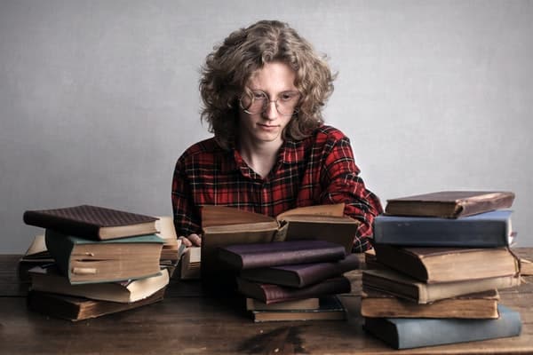 Garoto sentado com livros antigos sobre a mesa