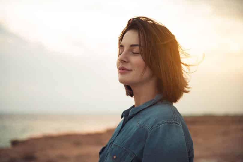 Mulher de olhos fechados em um campo aberto