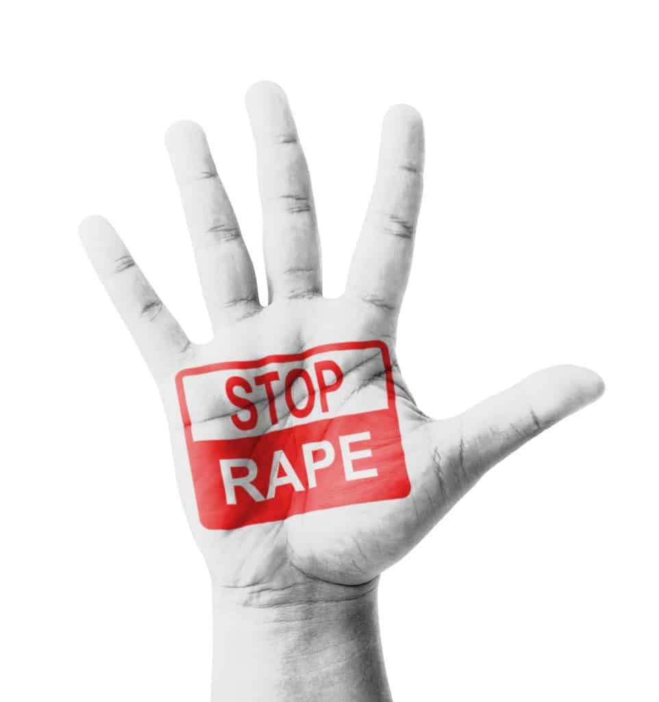 Imagem da palma de uma mão e sobre ela está escrito em um quadrado na cor vermelho a palavra em inglês - STOP RAPE - que significa PARE DE ESTUPRO.
