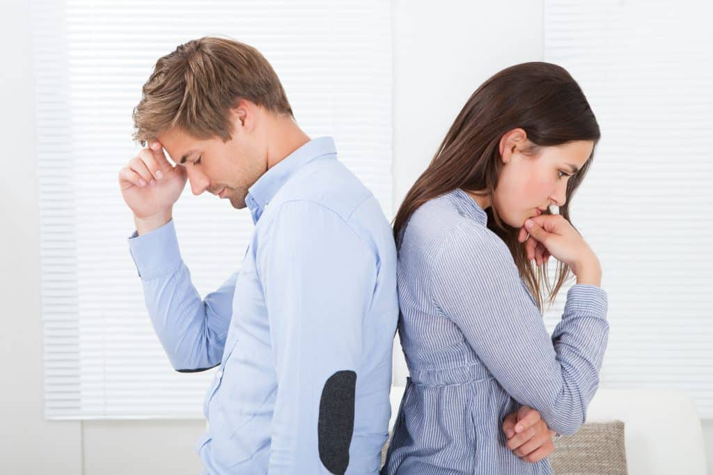 Homem e mulher de costas um para o outro, ambos com expressão séria e preocupada.