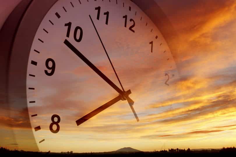 Ilustração de um relógio sobreposto ao pôr do sol.