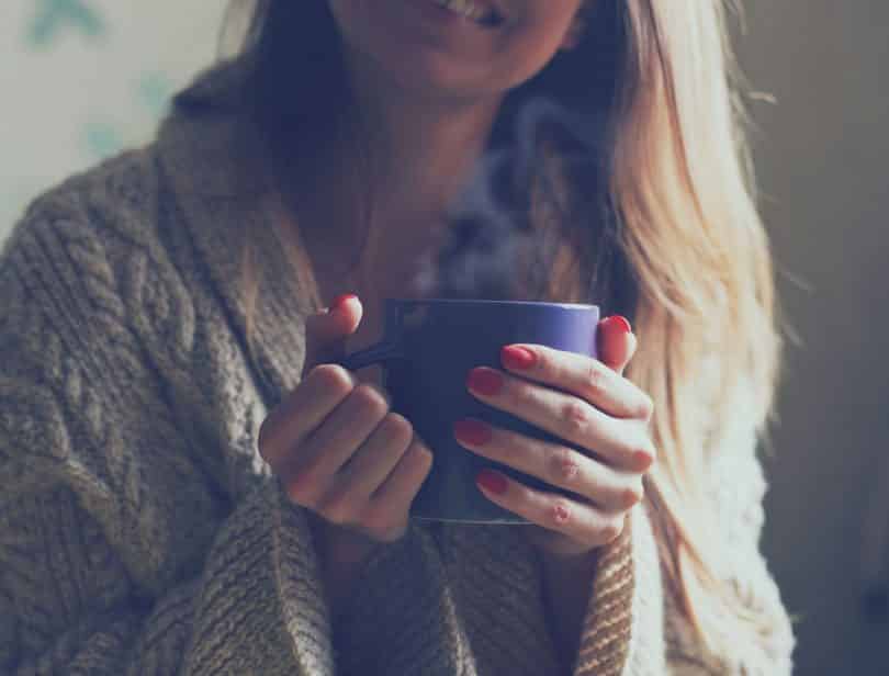 Mulher sorrindo segurando caneca de chá