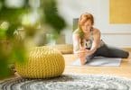 Mulher praticando yoga em um tapete, na sala de casa.