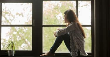 Mulher sentada na janela pensando