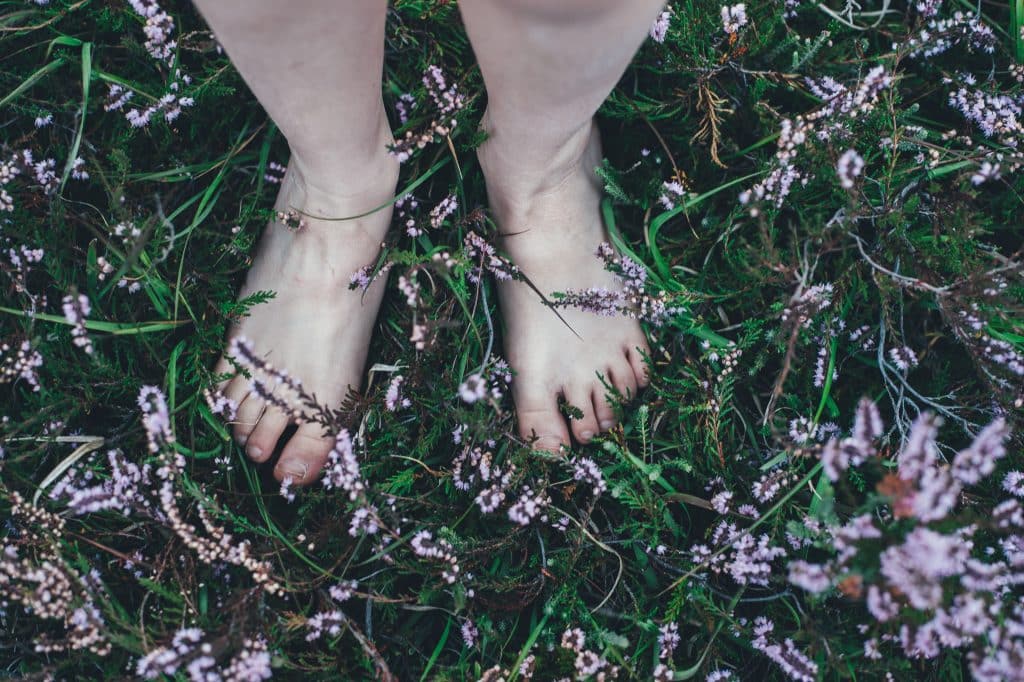 Mulher com os pés descalços em um gramado com flores