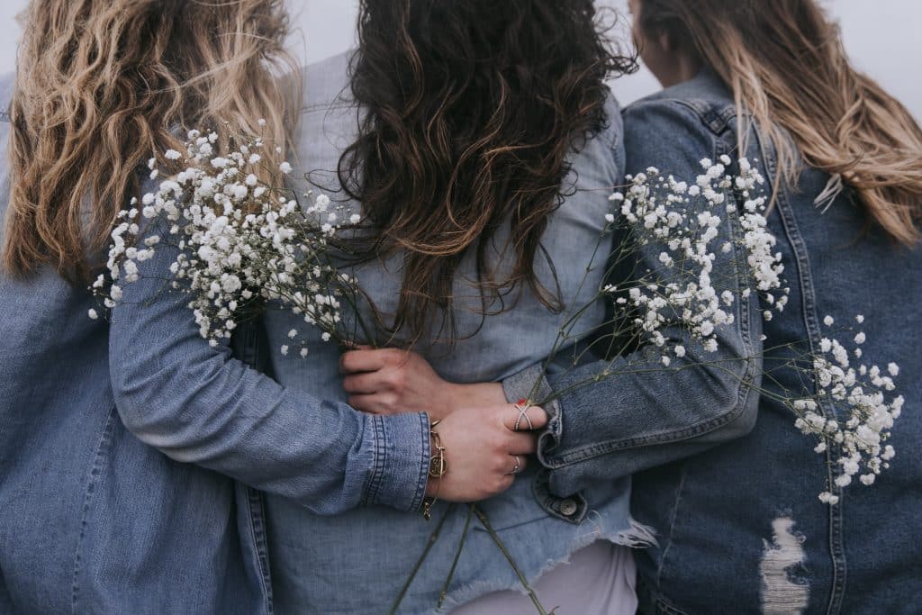 Mulheres abraçadas segurando flor