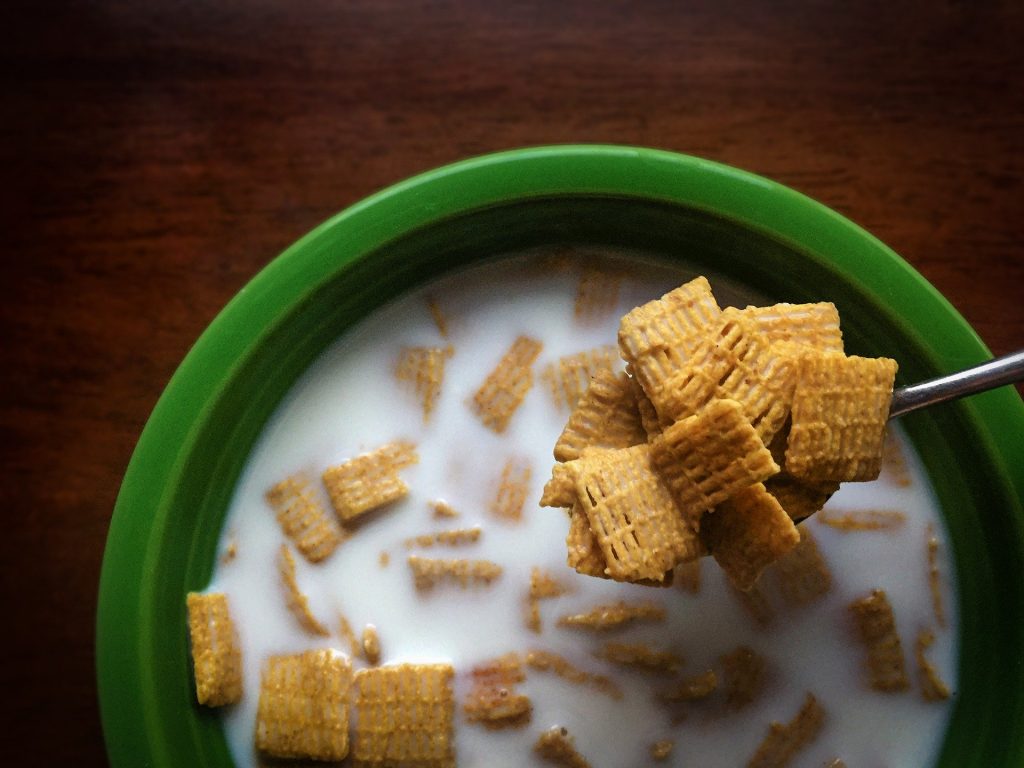 Imagem de um bowl na cor verde e dentro dele cereais com leite.
