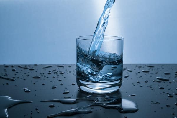 Água enchendo o copo de vidro