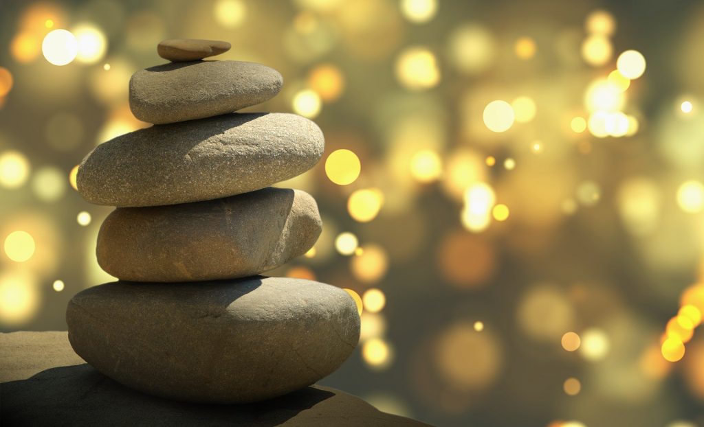 Imagem das pedras de feng shui e ao fundo muitas luzes representando a espiritualidade e a física quântica.