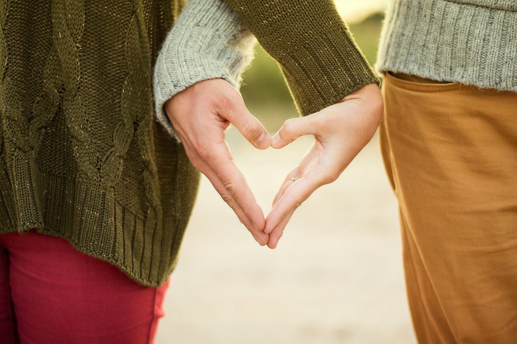 Imagem de um casal assexual de mãos dadas. Aos mãos formam a imagem de um coração.