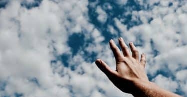 Pessoa com a mão aberta em direção ao céu
