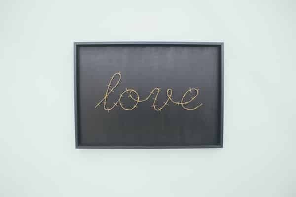 Quadro com escrito "love" costurado