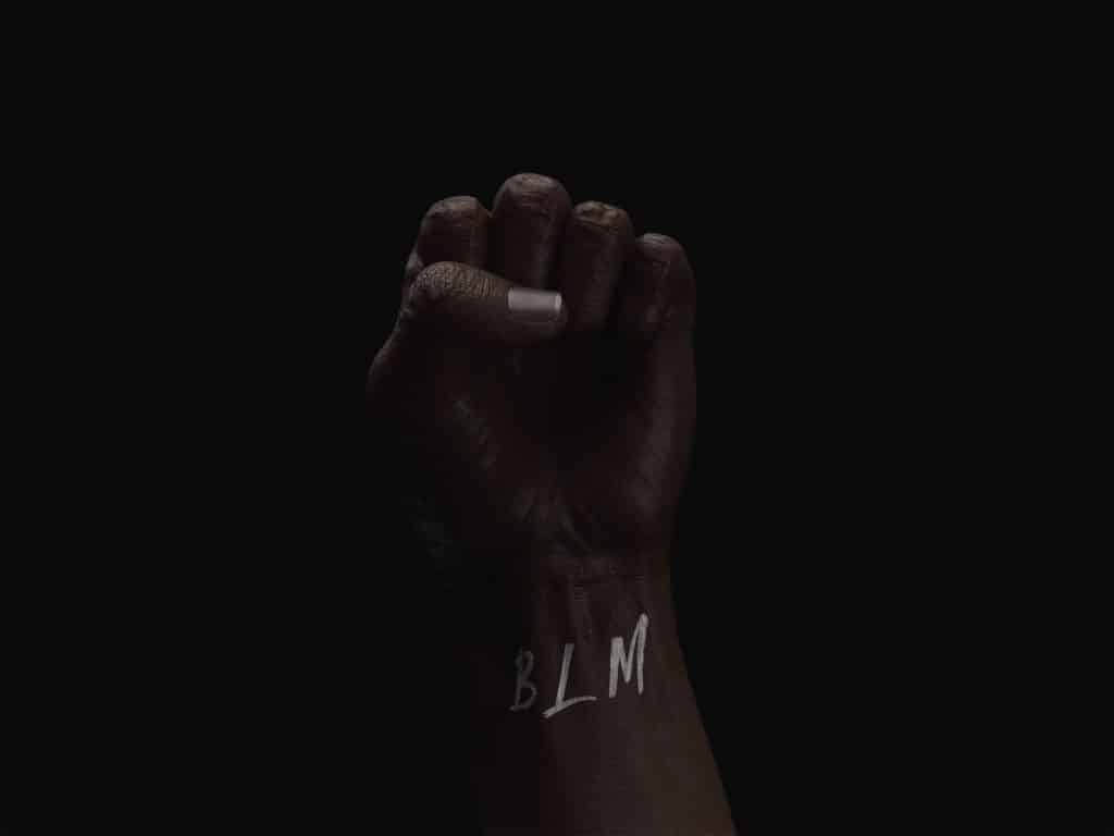 Pessoa com a mão fechada com as siglas "BLM" no pulso