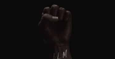 Pessoa com a mão fechada com as siglas "BLM" no pulso