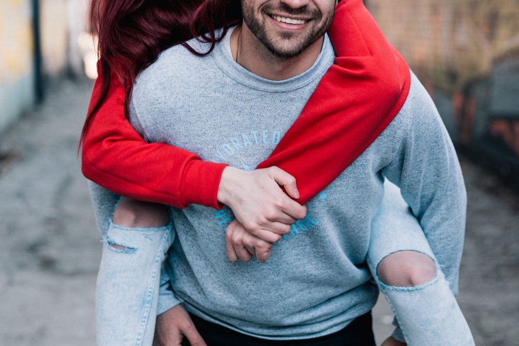 Imagem de um casal jovem. Ele carrega a moça em suas costas. Estão felizes. A imagem retrata a questão da relação entre o casal e o orgasmo feminino.
