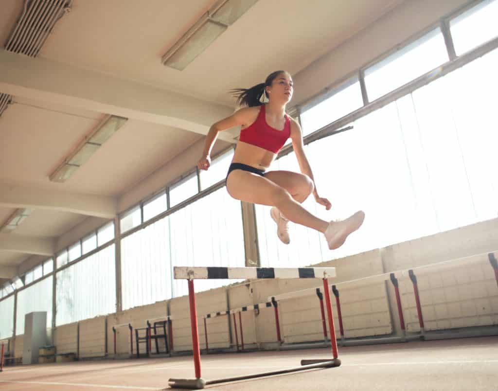 Mulher atleta pulando um obstáculo.