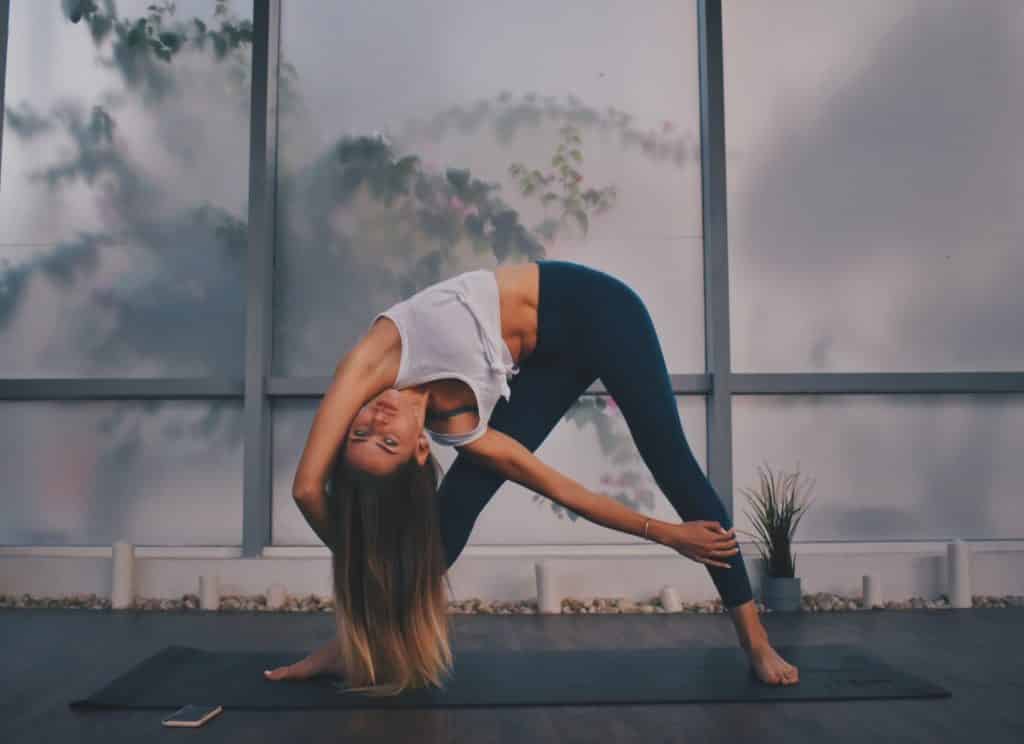 Mulher fazendo movimento de yoga em um espaço aberto