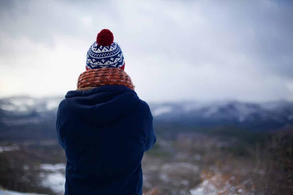 Pessoa usando roupas de frio e olhando para as montanhas