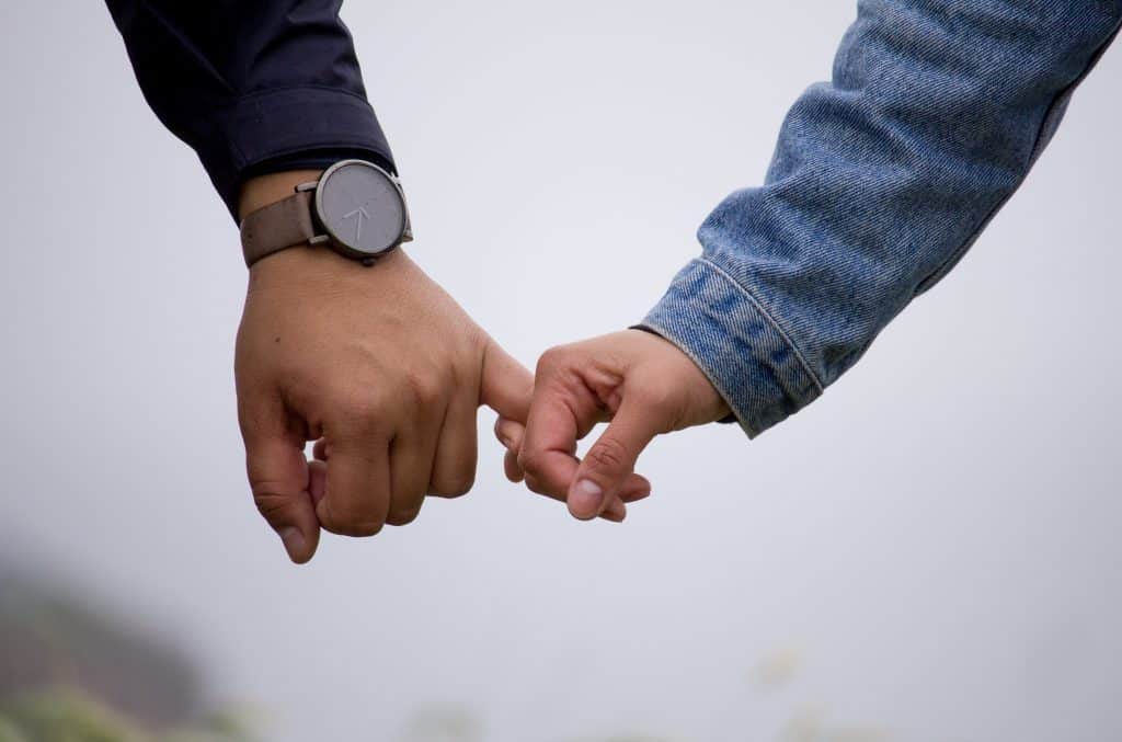 Homem e mulher com seus dedos mindinhos juntos