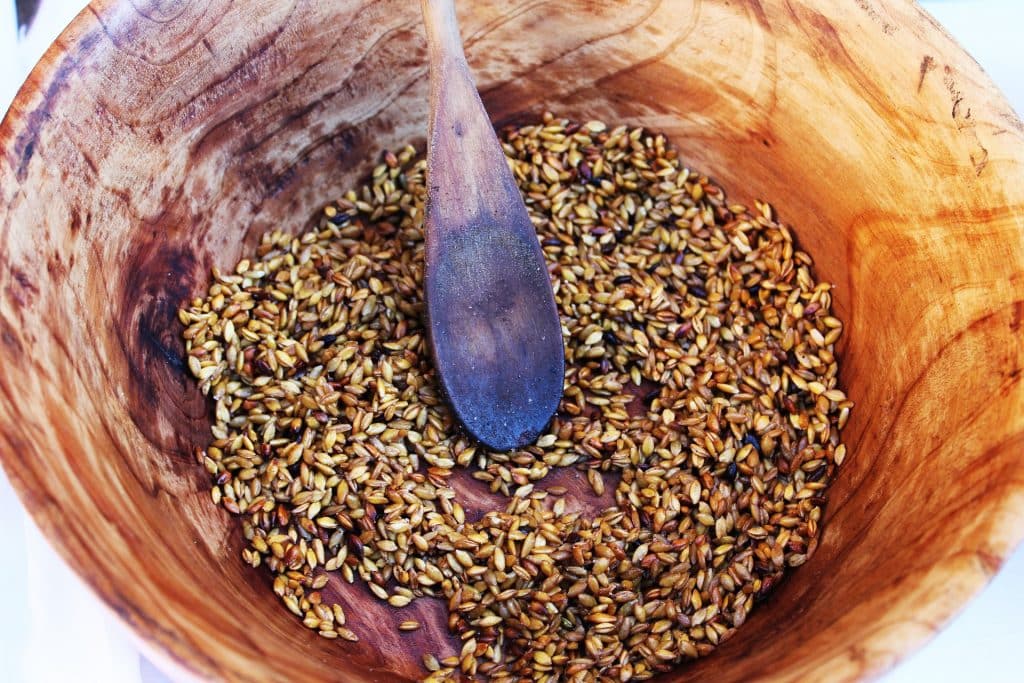 Imagem de um bowl de madeira com sementes de cereais.
