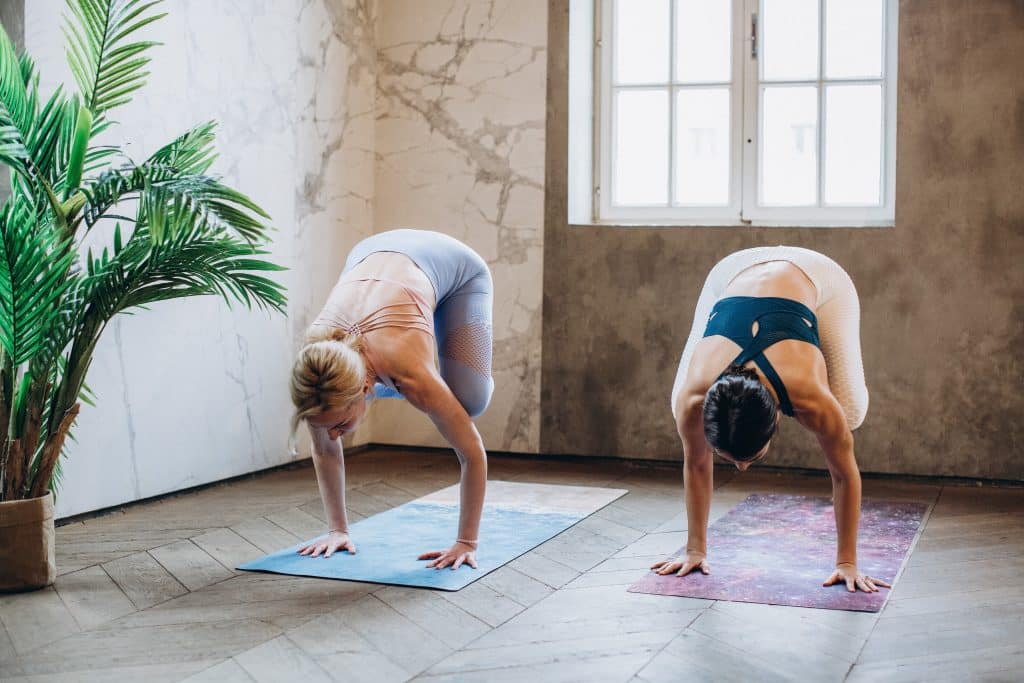 Duas mulheres praticando yoga na pose Bakasana.