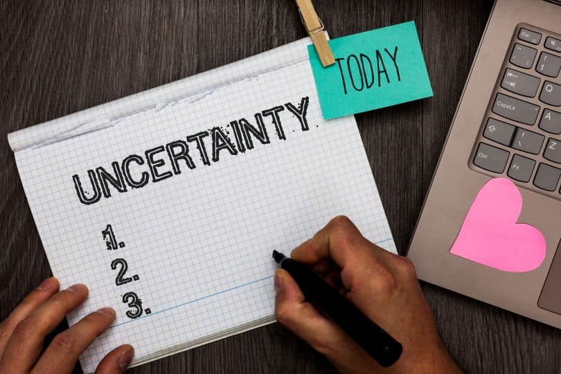 Caderno com a palavra "uncertainty" e notebook ao lado.