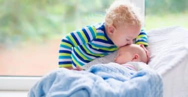 Irmão beijando testa de irmão mais novo dormindo