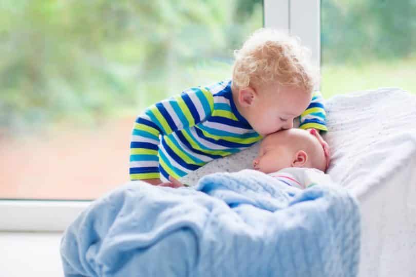 Irmão beijando testa de irmão mais novo dormindo