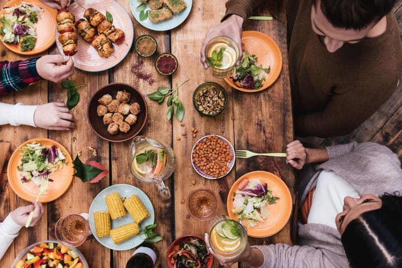 Mesa com pessoas comendo coisas saudáveis.