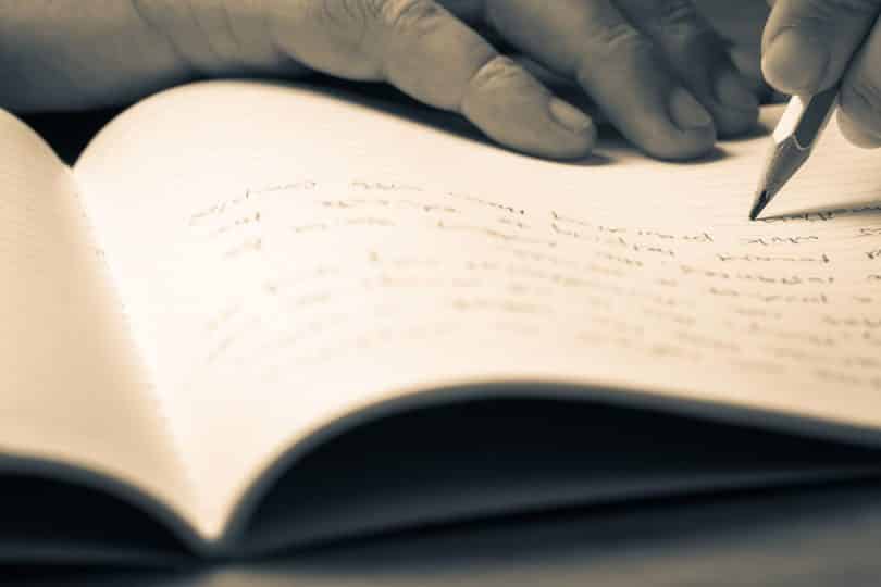 Pessoa escrevendo num caderno