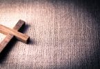 Imagem de uma cruz sobre um tecido de juta. Ela representa a oração do perdão.
