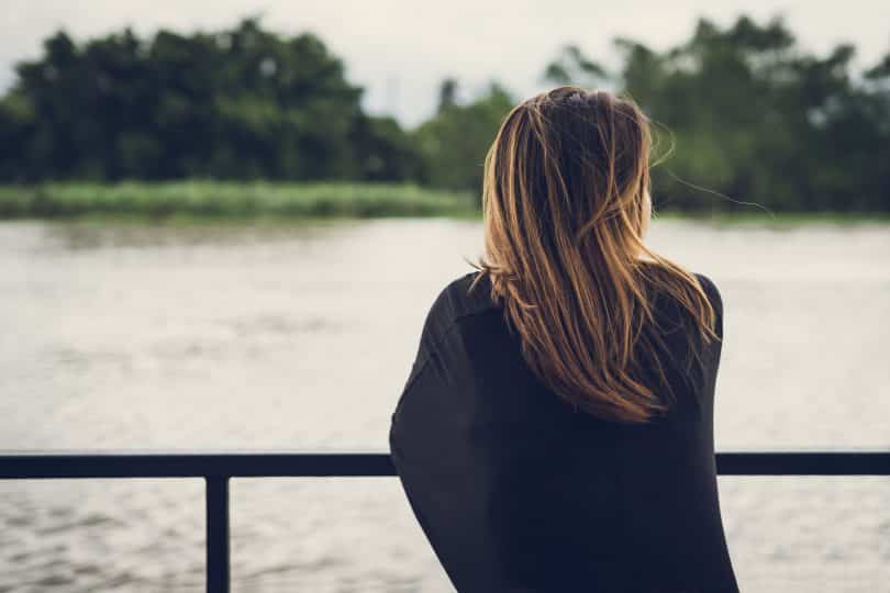 Mulher olhando para o rio sozinha