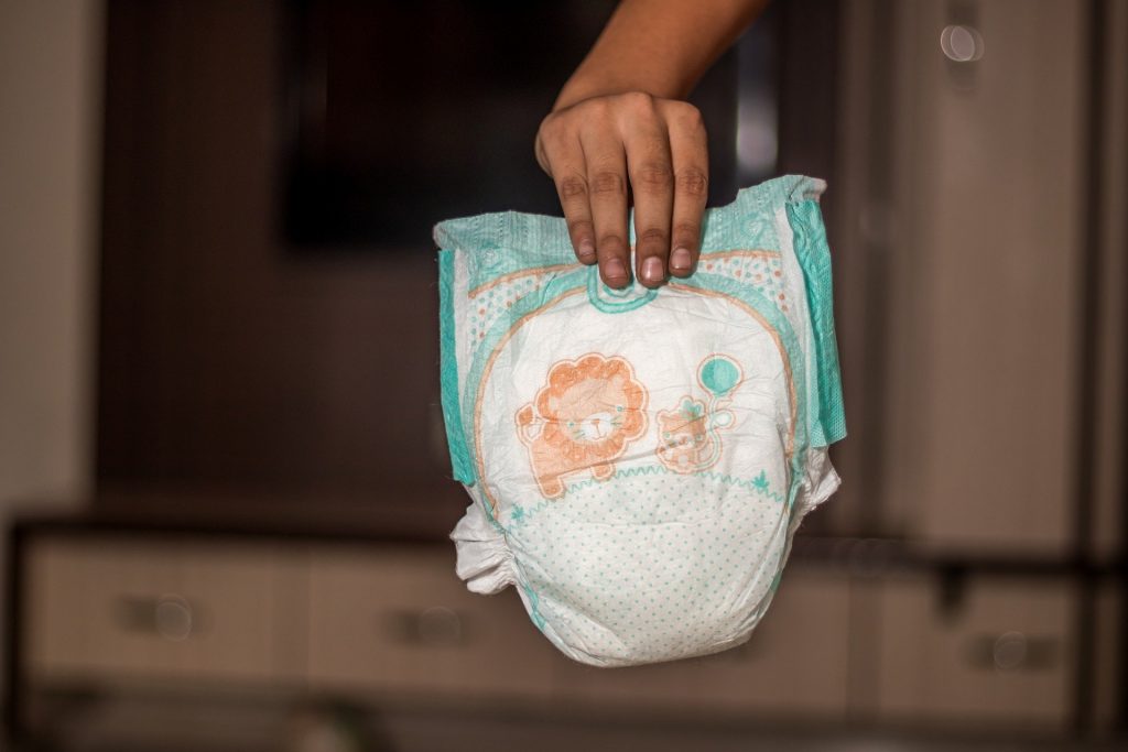 Imagem de uma fralda ecológica sendo segurada por uma mão masculina.