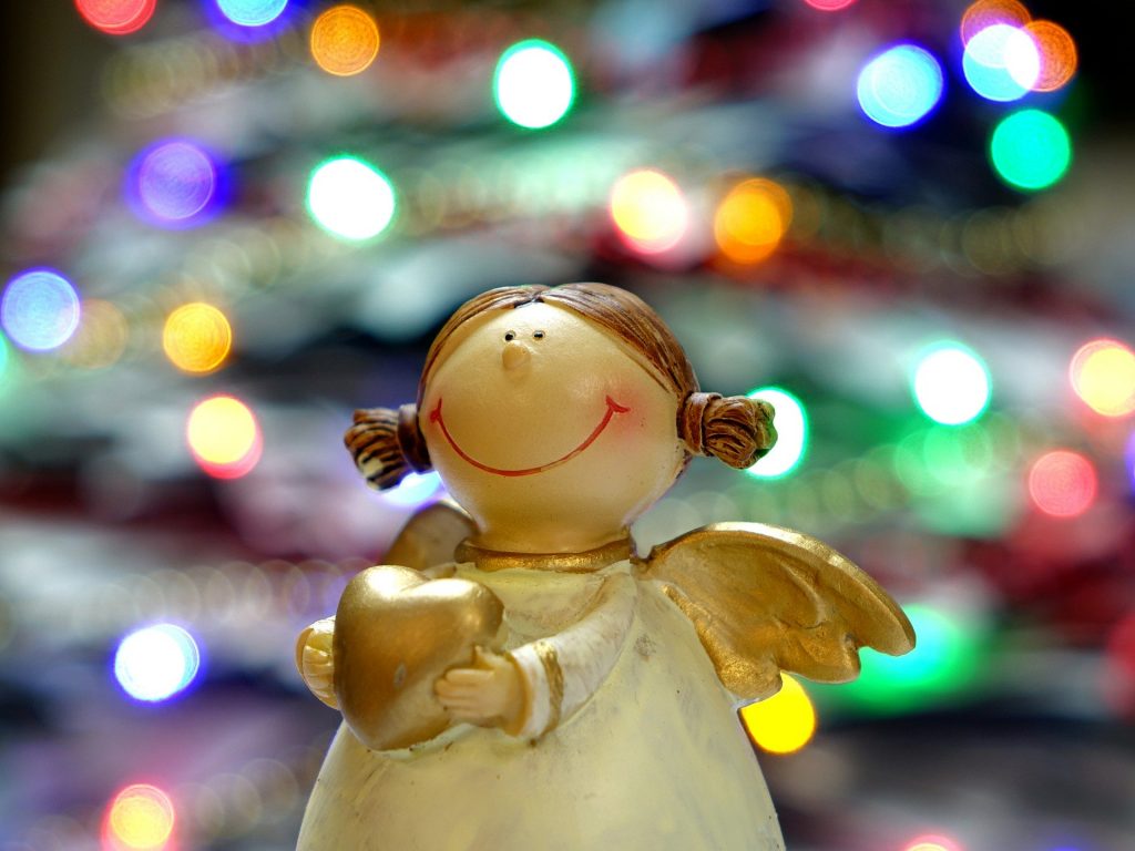 Imagem de um lindo anjinho natalino feito em  gesso pintado na cor branco. Suas asas são douradas. Ele segura entre as mãos um coração dourado.