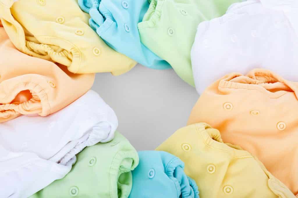 Imagem de fraldas ecológica de várias cores como: branca, amarela, laranja, verde e azul.