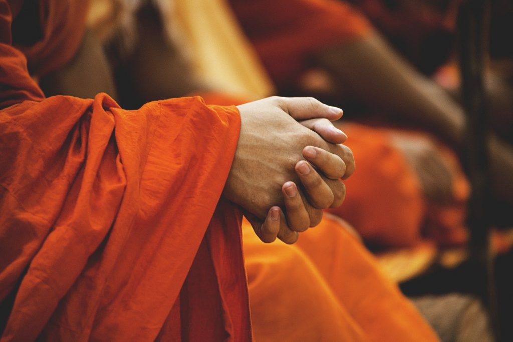 Imagem das mãos de uma pessoa adepta ao budismo. Ele está em oração exercitando a espiritualidade.