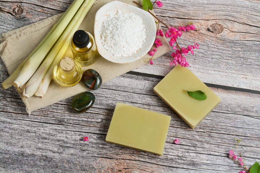 Oléos, plantas e produtos naturais sobre uma mesa de madeira com pequenas flores.