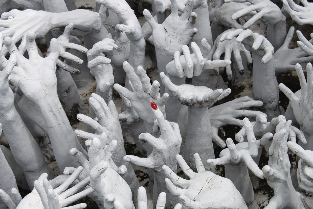 Imagem em preto e branco de vãrias mãos femininas e no centro uma mão com um dedo em destaque com a sua unha pintada na cor vermelha.