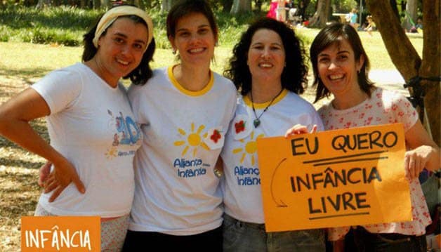 Foto de quatro mulheres segurando um cartaz laranja escrito "eu quero infância livre".