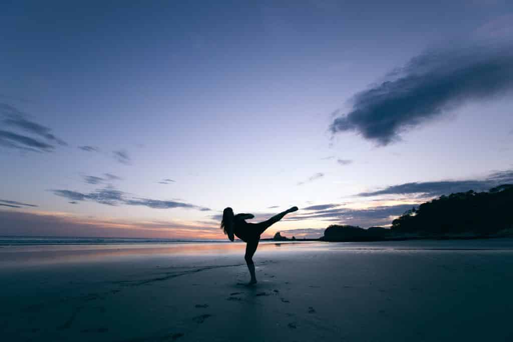 Mulher praticando artes marciais na praia