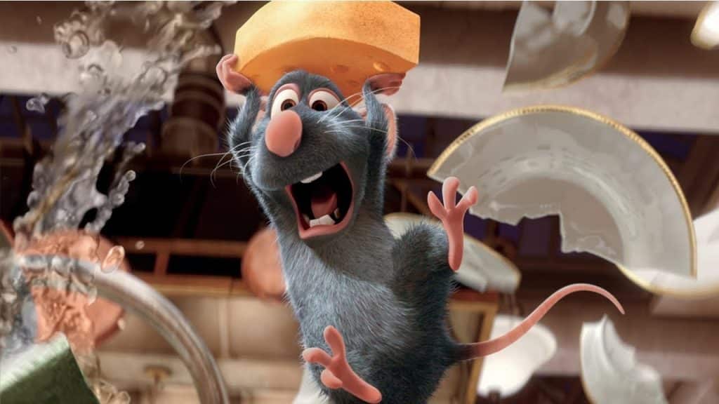 Remy segurando um queijo na cabeça com expressão de espanto e ao fundo alguns pratos quebrados