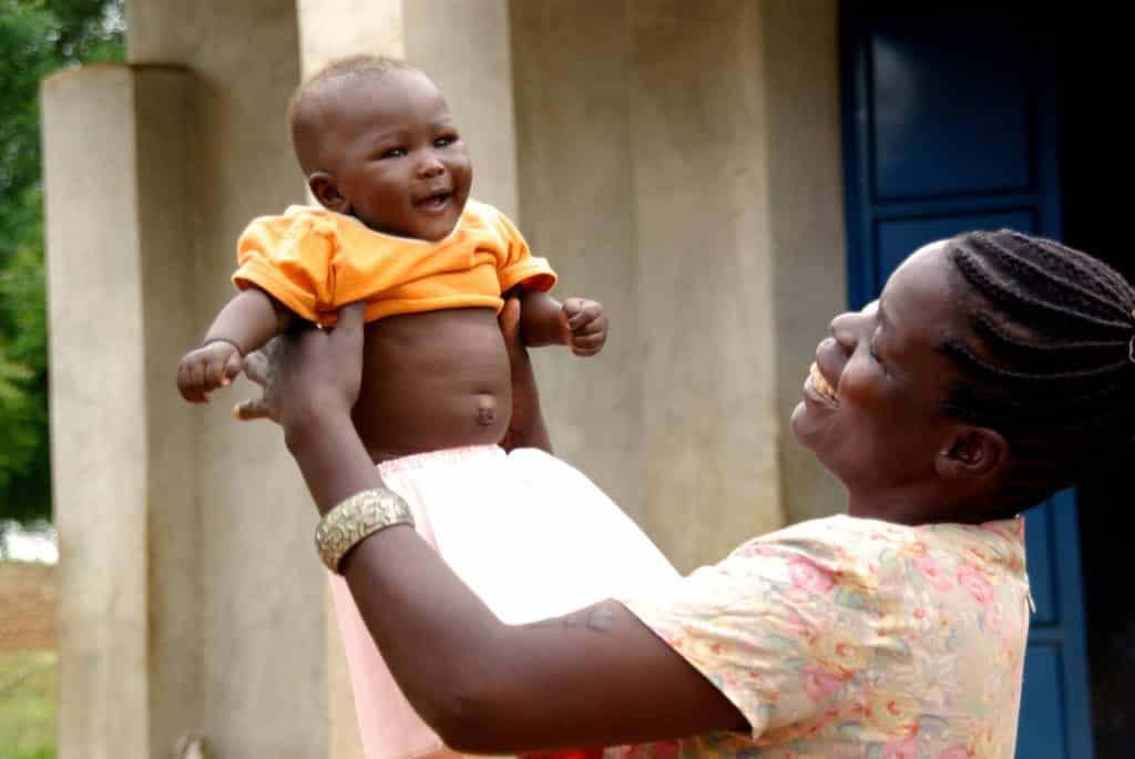 Imagem de uma mãe africana segurando em seus braços seu lindo garoto recém nascido.