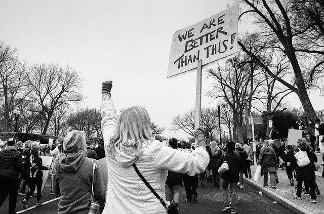 Mulher de costas com placa em protesto