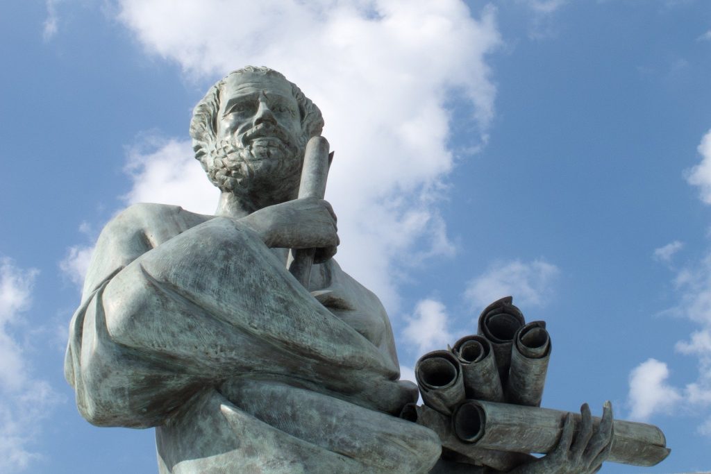 Foto de uma estátua do filósofo da Grécia Antiga Sócrates, sob o céu ensolarado. 