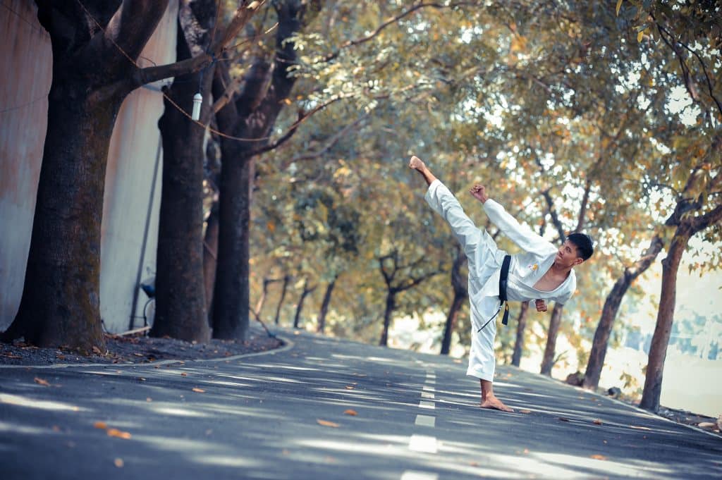 Homem no meio da rua fazendo posição de artes marciais