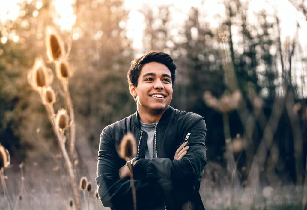 Homem em meio a plantação sorrindo de braços cruzados