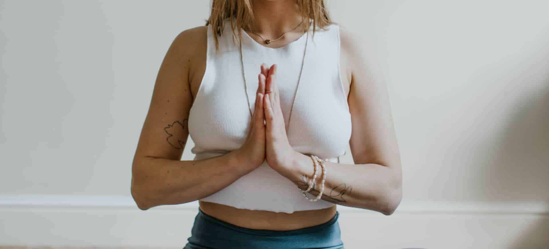 Mulher meditando com mãos unidas em frente ao corpo