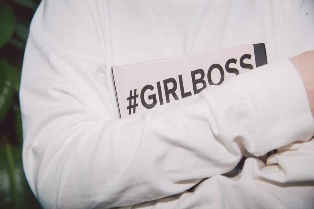 Mulher abraçando um caderno escrito "girlboss"